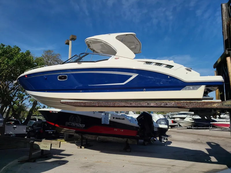 Slide: The Image of 2016 Chaparral 307 SSX boat in dry dock, blue and white exterior, sunny day. - 0