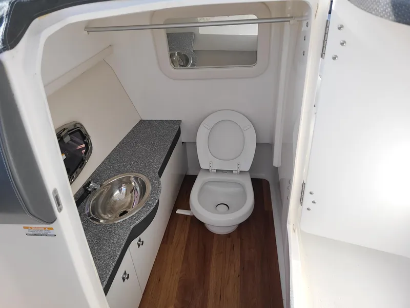 Slide: The Image of 2016 Chaparral 307 SSX boat bathroom with sink, toilet, and wood flooring. - 13