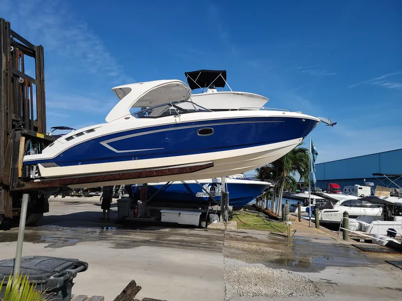 Slide: The Image of 2016 Chaparral 307 SSX boat lifted at marina, blue and white design. - 2