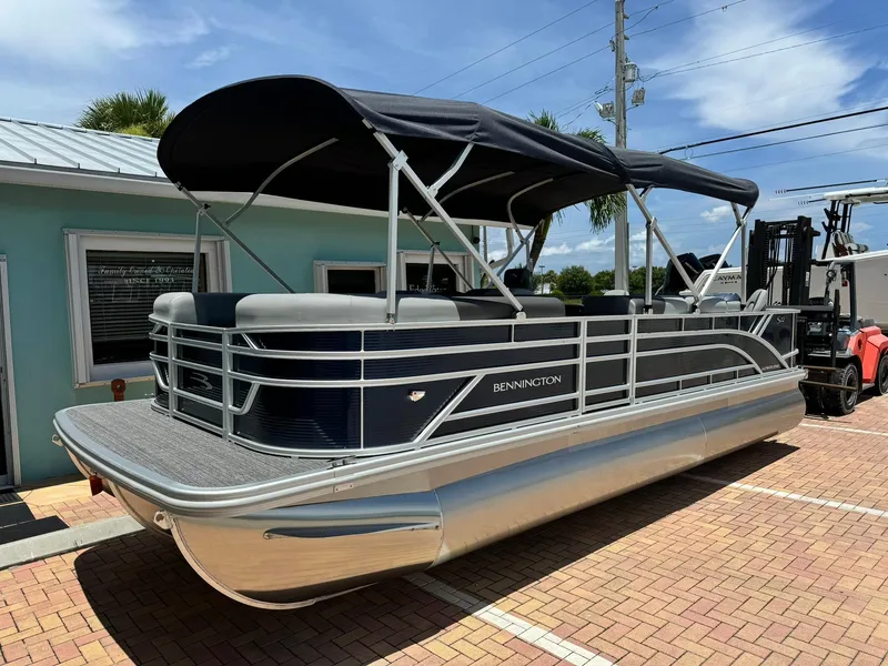 Slide: The Image of 2025 Bennington 22ss-sps pontoon boat with black canopy on a sunny day. - 0