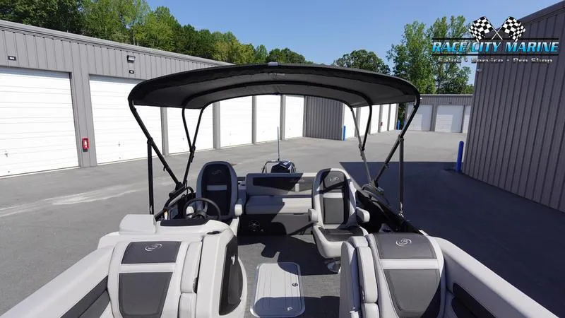 Slide: The Image of 2025 Barletta C24UC pontoon boat with canopy, parked near storage units. - 38