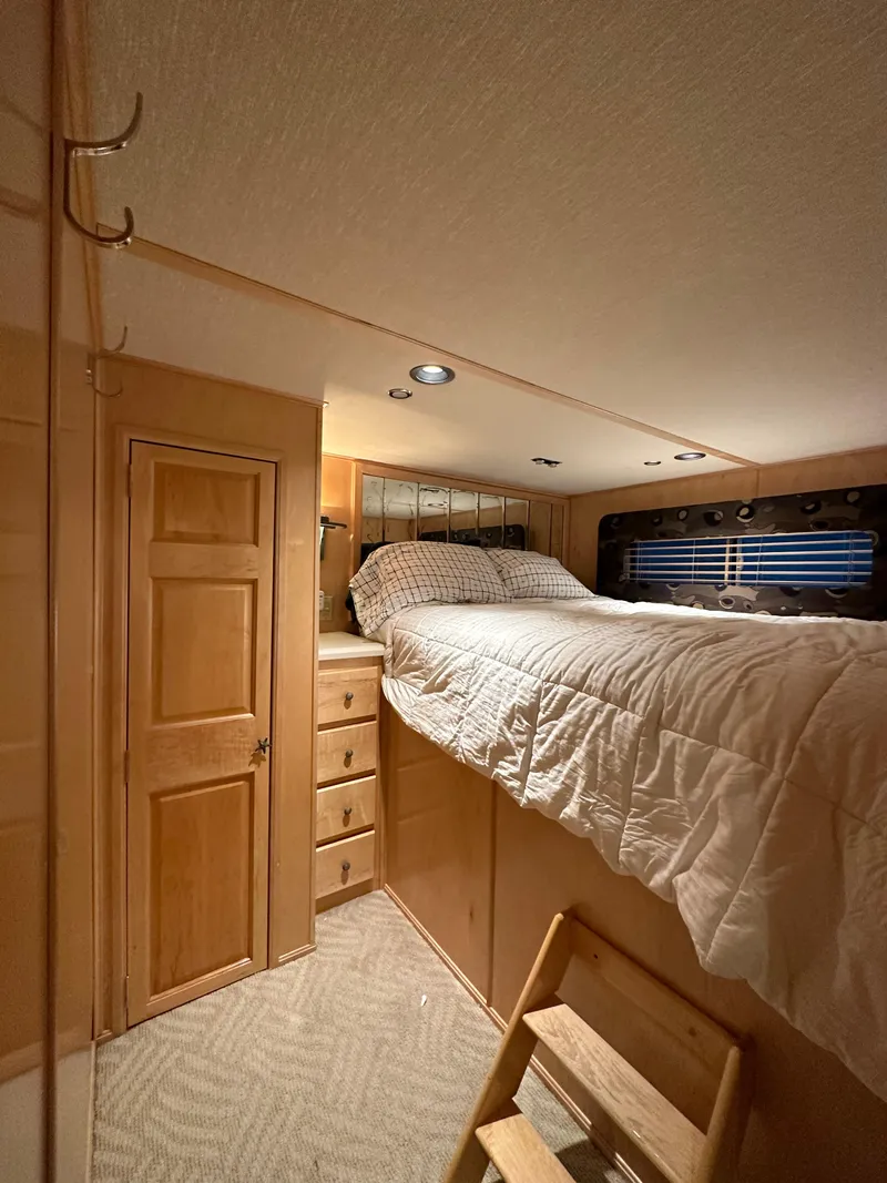 Slide: The Image of Cozy 2001 Custom Endless Summer RV interior with elevated bed and wooden cabinetry. - 11