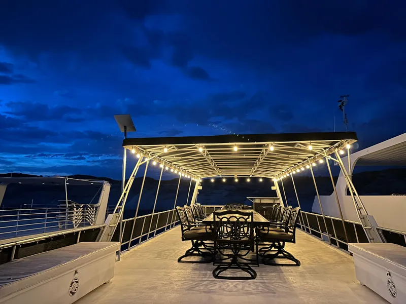 Slide: The Image of Custom 2001 Endless Summer boat deck with illuminated dining area at dusk. - 21
