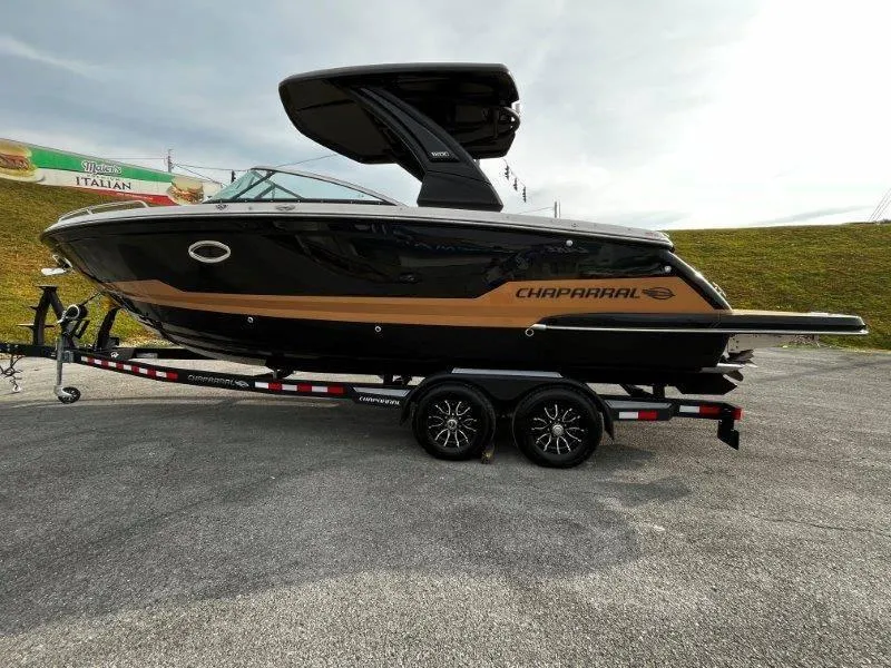 Slide: The Image of 2025 Chaparral 287 SSX boat on trailer, sleek black and tan design. - 28