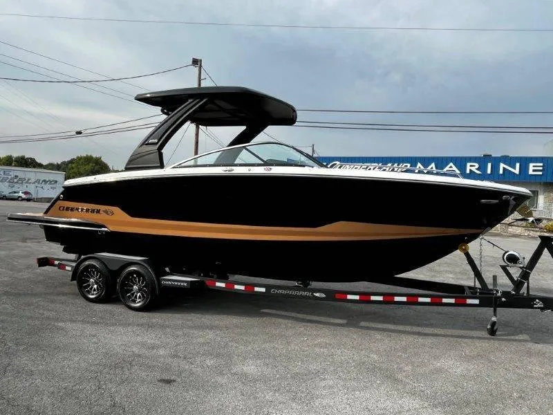 Slide: The Image of 2025 Chaparral 287 SSX boat on trailer, black and gold design, parked outdoors. - 39