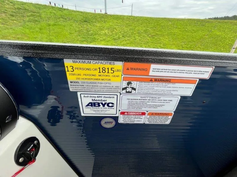 Slide: The Image of 2023 Crest Classic Fish 220 SF capacity and safety warning labels on boat dashboard. - 30
