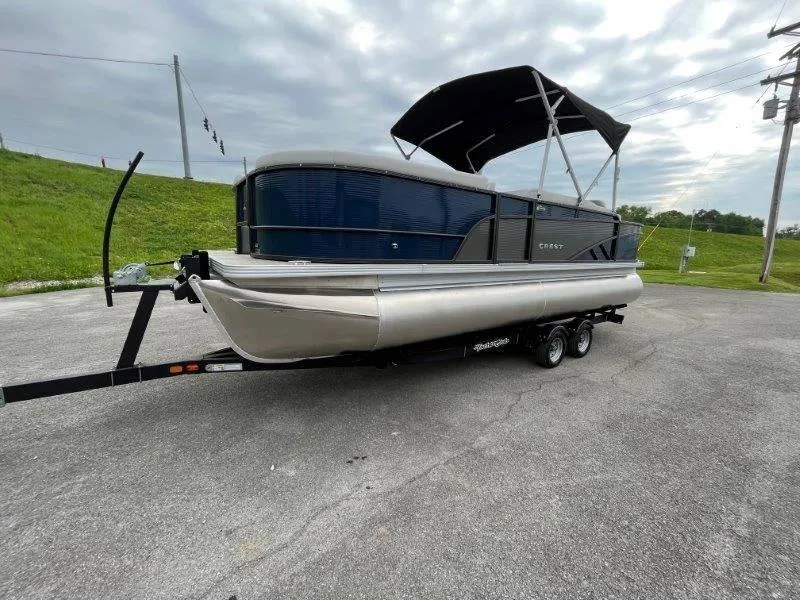 Slide: The Image of 2023 Crest Classic Fish 220 SF pontoon boat on trailer, overcast sky background. - 6