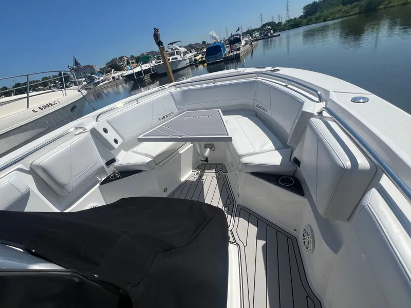 Slide: The Image of 2020 Blackfin 272 CC boat interior with seating and table, docked in a marina. - 18