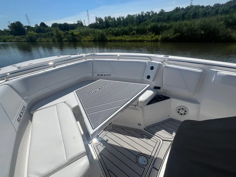 Slide: The Image of 2020 Blackfin 272 CC boat interior with seating and table on a calm river. - 22