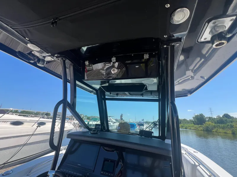 Slide: The Image of 2020 Blackfin 272 CC boat interior with console and canopy, docked by a scenic river. - 23