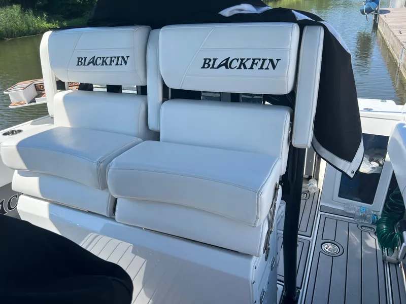 Slide: The Image of 2020 Blackfin 272 CC boat seats with logo, docked by the water. - 24