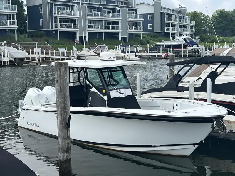 Slide: The Image of 2020 Blackfin 272 CC boat docked in marina, modern waterfront buildings in background. - 26