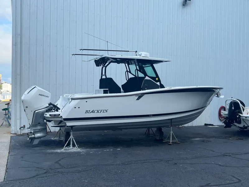 Slide: The Image of 2020 Blackfin 272 CC boat on stands, white hull, dual engines, parked outdoors. - 29
