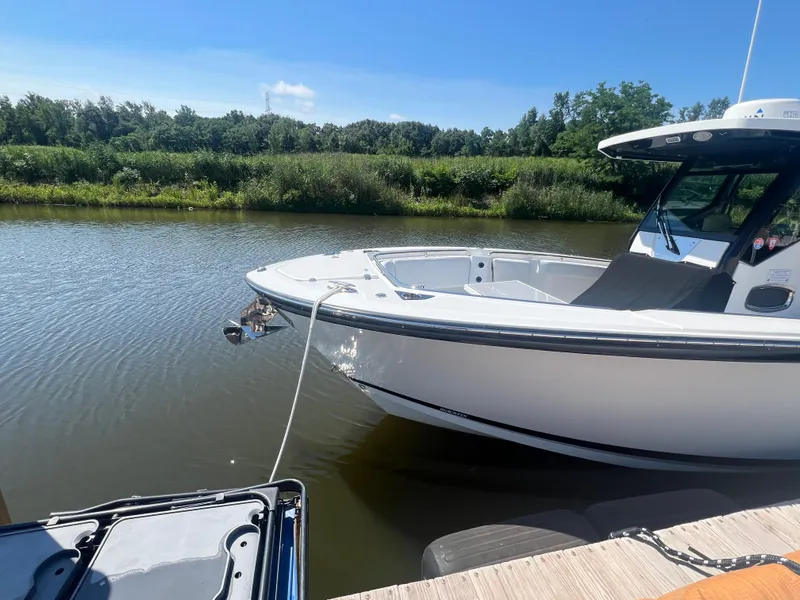 Slide: The Image of 2020 Blackfin 272 CC boat docked on a calm river under a clear blue sky. - 8