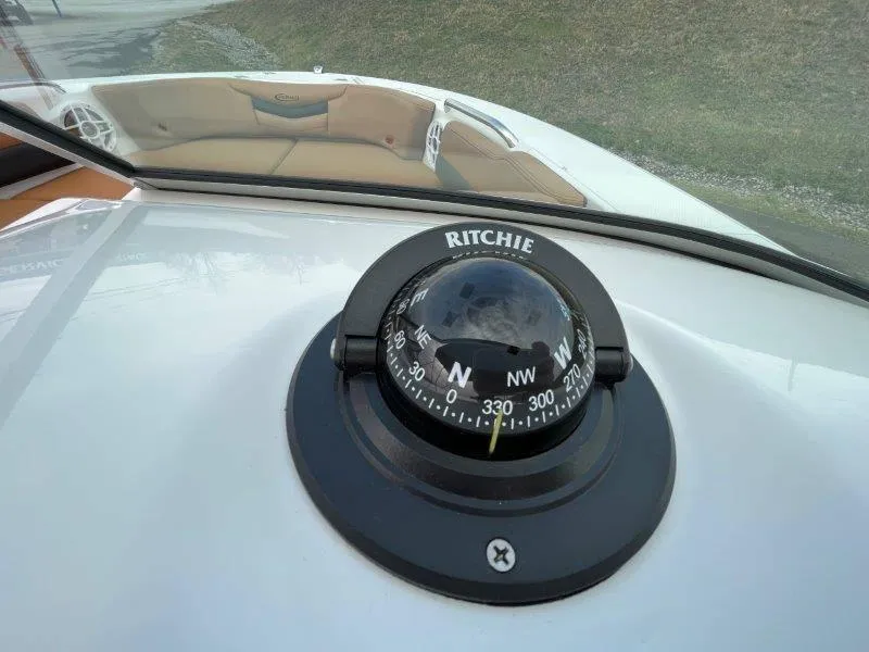 Slide: The Image of Ritchie compass on 2024 Robalo R207 boat dashboard, with beige seating in background. - 28