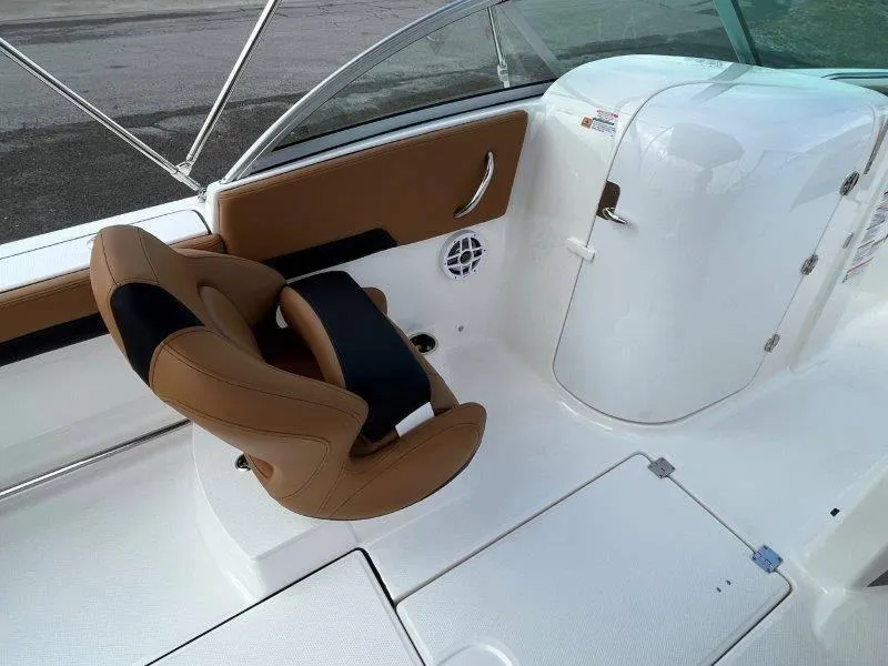 Slide: The Image of 2024 Robalo R207 boat interior with tan and black seating, white console, and storage compartment. - 35