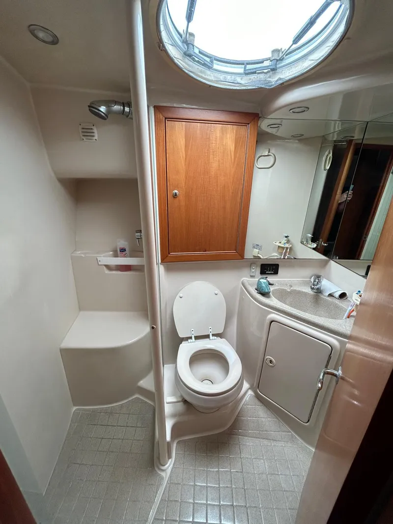 Slide: The Image of 2005 Riviera 37 Flybridge bathroom with shower, toilet, and vanity under skylight. - 11