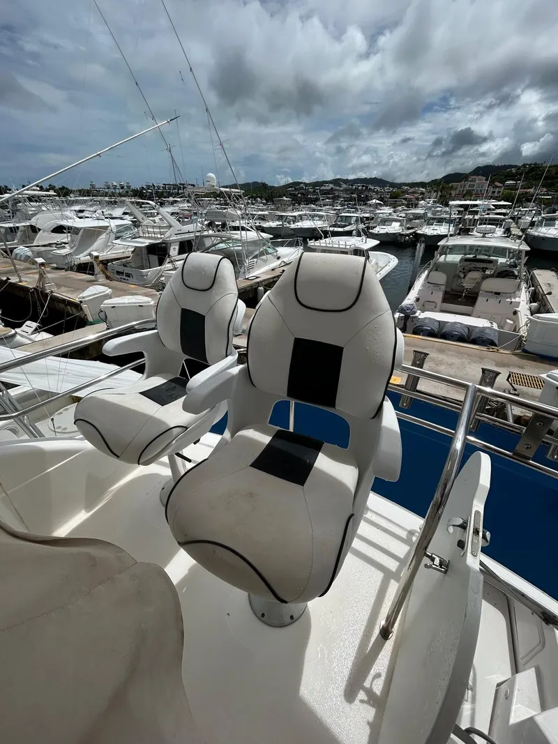 Slide: The Image of Two white captain chairs on a 2005 Riviera 37 Flybridge yacht, docked at a marina. - 5