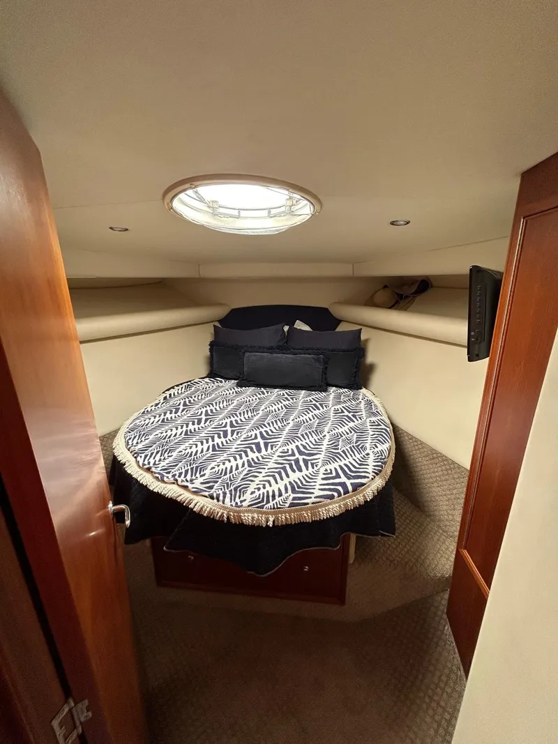 Slide: The Image of 2005 Riviera 37 Flybridge cabin with bed, skylight, and wooden accents. - 9