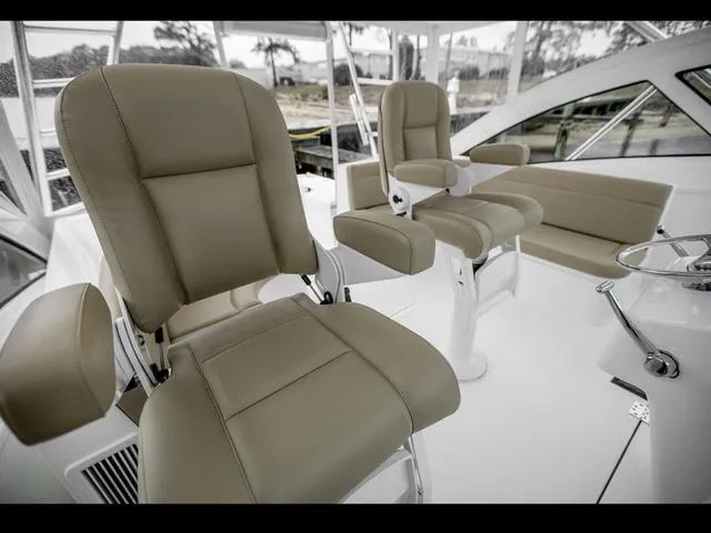 Slide: The Image of 2024 Albemarle 41 Express boat interior with beige captain chairs and helm. - 14