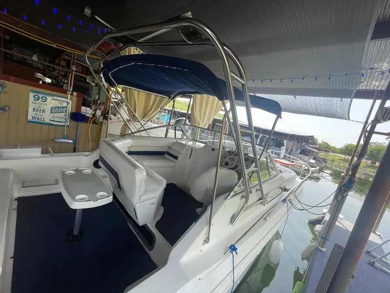 Slide: The Image of 1998 Rinker Fiesta Vee 280 boat docked, featuring a blue canopy and white seating. - 4