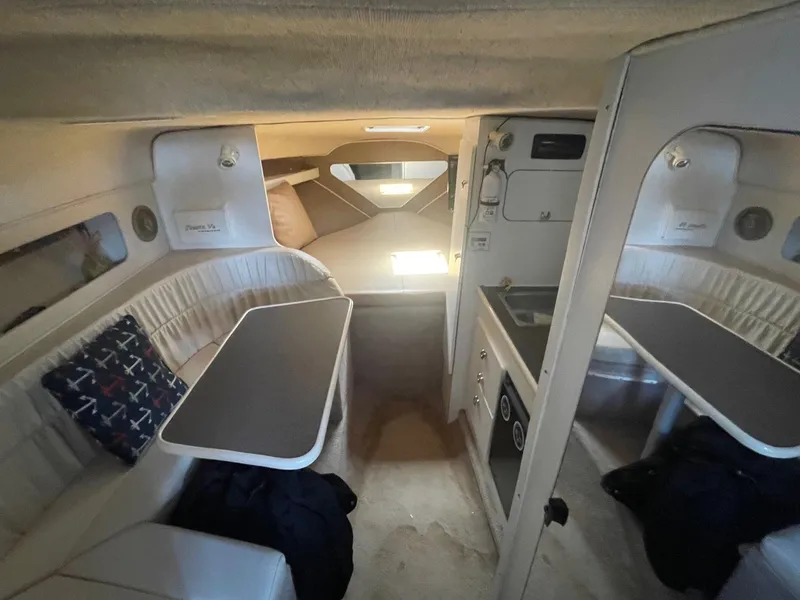 Slide: The Image of 1998 Rinker Fiesta Vee 280 cabin interior with seating, table, and kitchenette. - 8