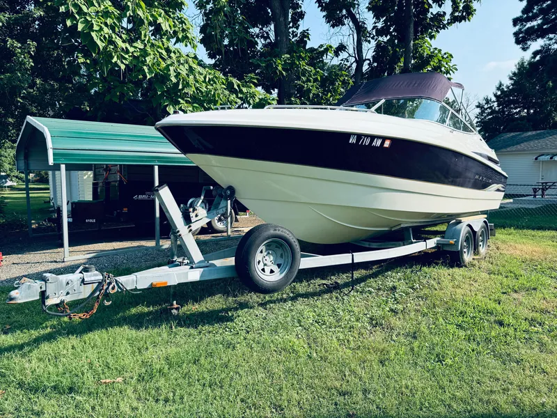 Slide: The Image of 1999 Maxum 230 boat on trailer, parked on grass under trees. - 5