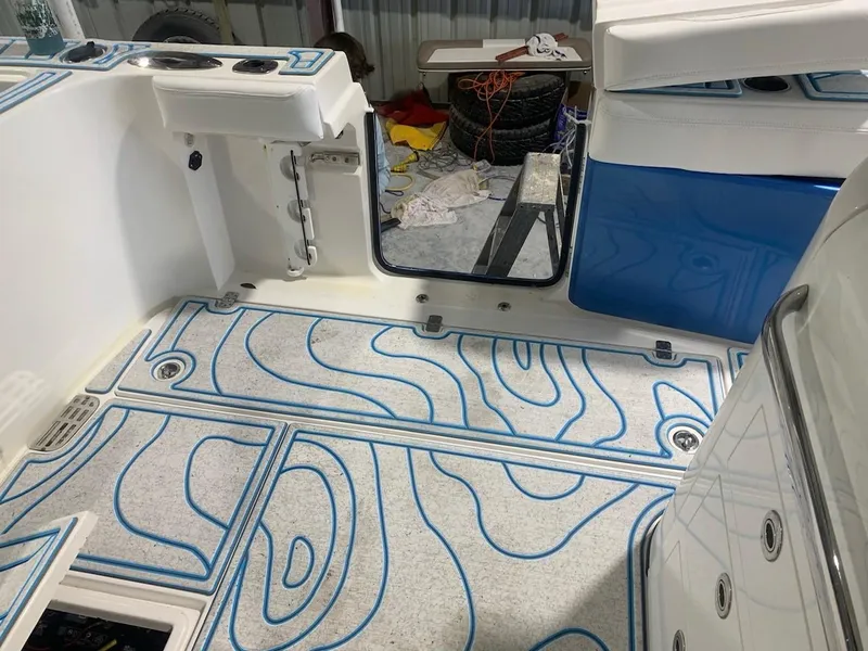 Slide: The Image of 2016 Edgewater 368 CC boat interior with blue-patterned flooring and storage compartments. - 12