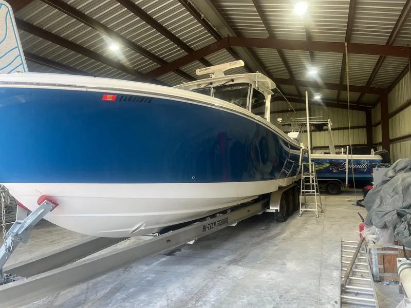 Slide: The Image of 2016 Edgewater 368 CC boat in storage, blue hull, on trailer. - 2