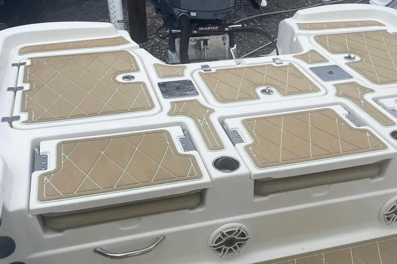 Slide: The Image of 2018 NauticStar 265 XTS boat deck with tan cushioned seating and storage compartments. - 8