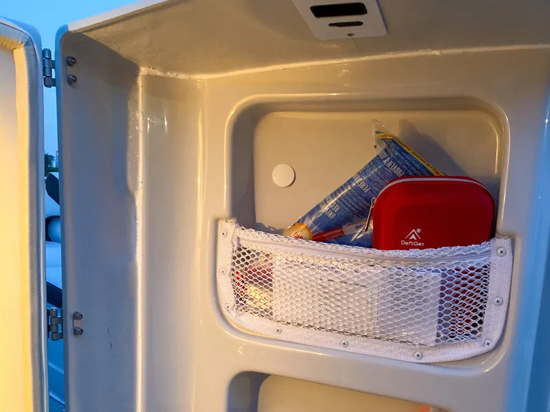 Slide: The Image of Storage compartment in a 2020 Crownline 255 SS boat with snacks and a first aid kit. - 13
