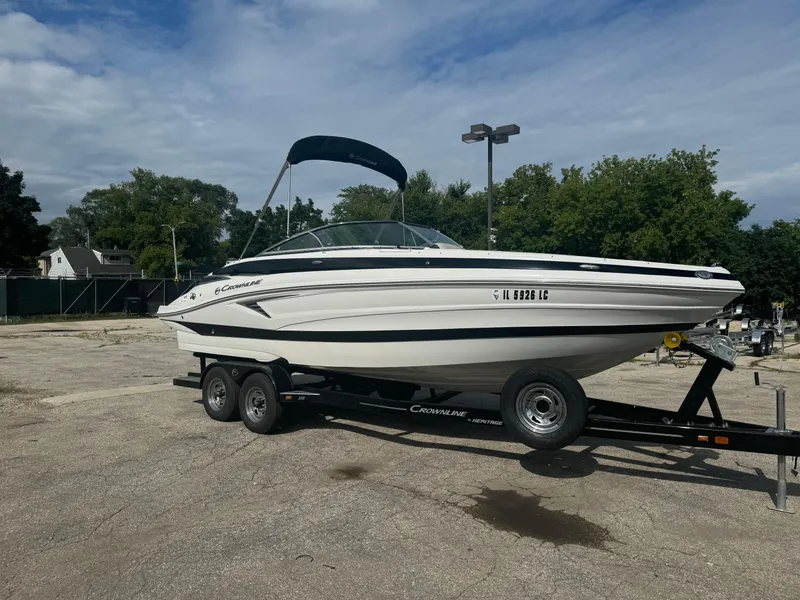 Slide: The Image of 2020 Crownline 255 SS boat on trailer, parked outdoors under cloudy sky. - 15