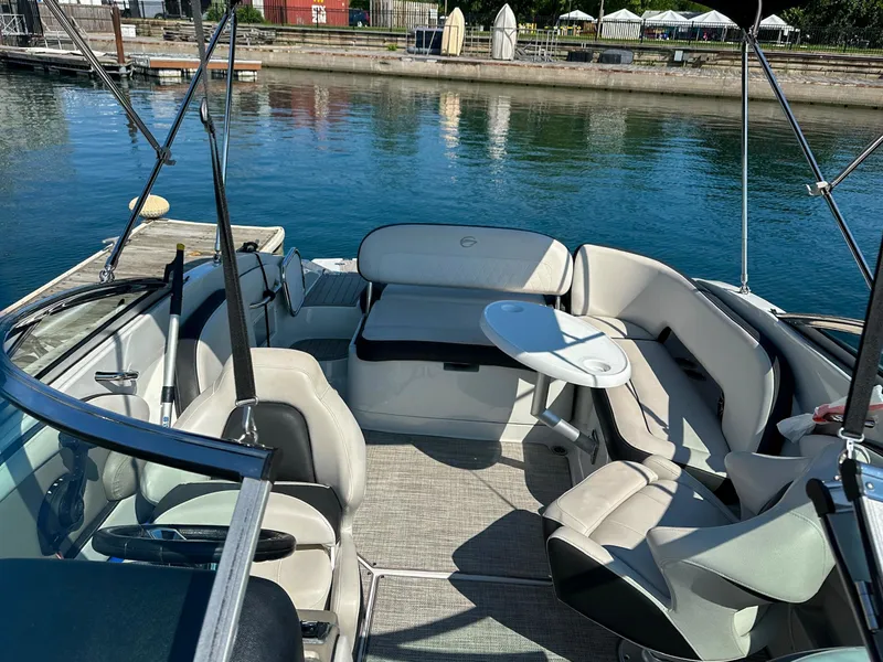 Slide: The Image of 2020 Crownline 255 SS boat interior with seating and table, docked by calm water. - 5