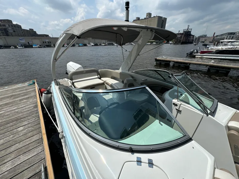 Slide: The Image of 2023 Crownline 255 XS boat docked at marina, featuring sleek design and spacious seating. - 11