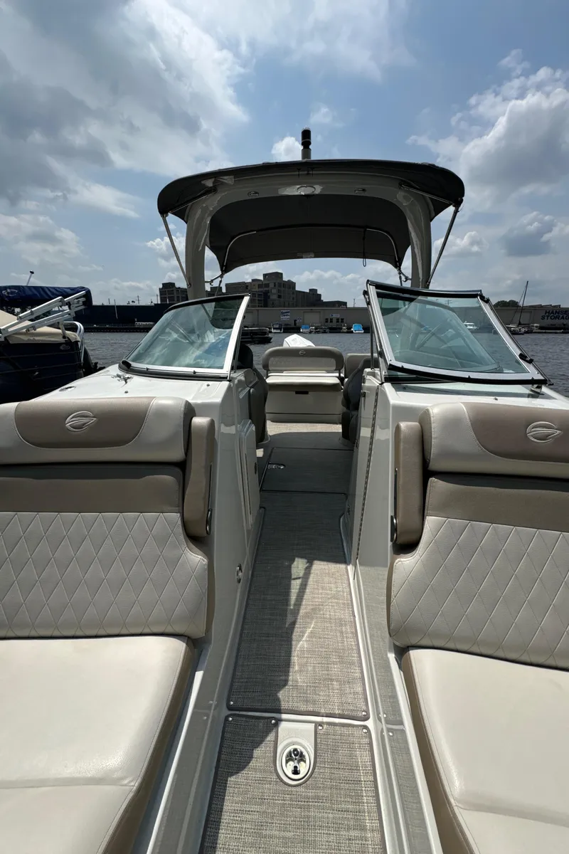 Slide: The Image of 2023 Crownline 255 XS boat interior with open seating and canopy on a sunny day. - 22