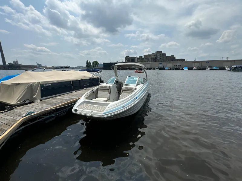 Slide: The Image of 2023 Crownline 255 XS boat docked on a calm waterfront under a cloudy sky. - 3