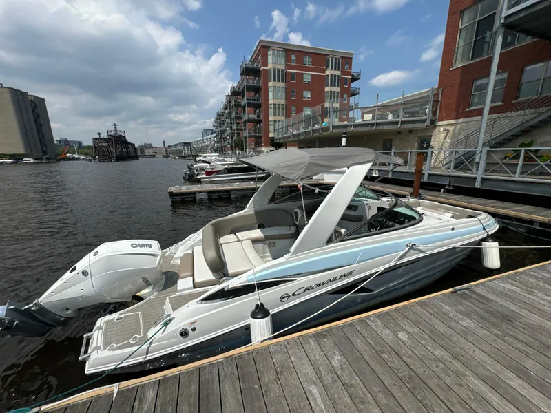 Slide: The Image of 2023 Crownline 255 XS boat docked by urban waterfront buildings. - 6