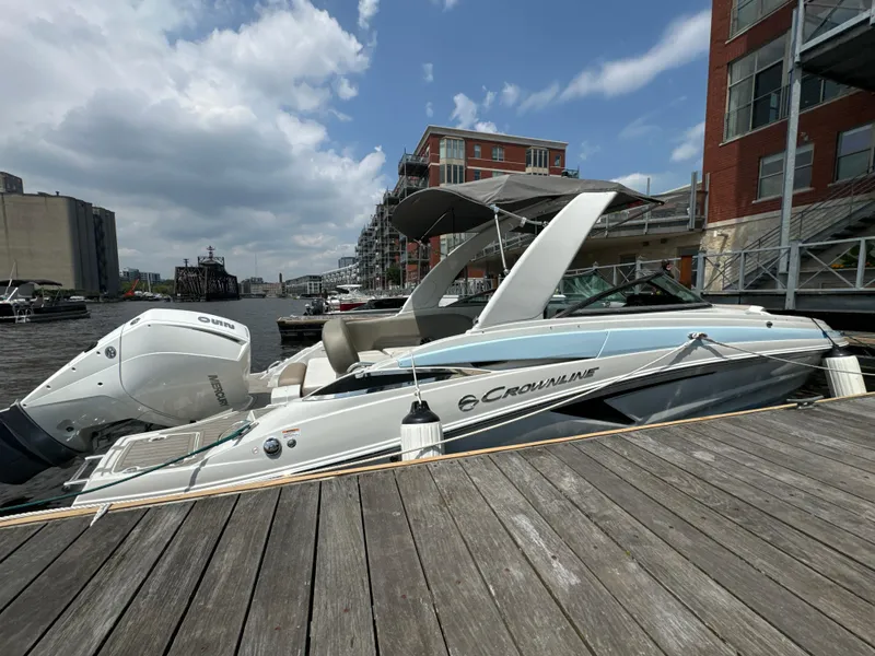 Slide: The Image of 2023 Crownline 255 XS boat docked by urban waterfront under cloudy sky. - 7