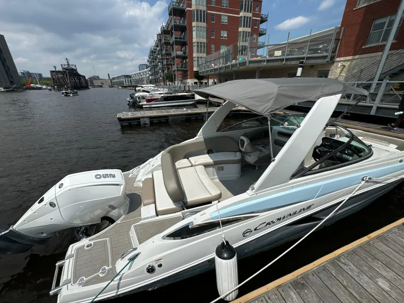 Slide: The Image of 2023 Crownline 255 XS boat docked by waterfront buildings under a cloudy sky. - 8