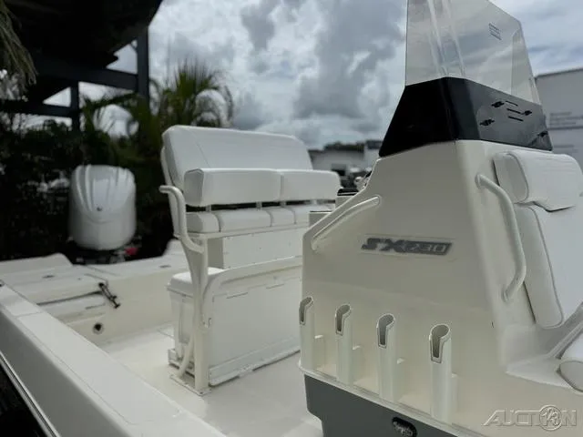 Slide: The Image of 2025 Skeeter SX230 boat interior with seating and console, under cloudy sky. - 13