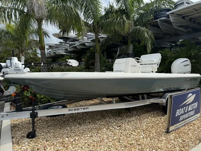 Slide: The Image of 2025 Skeeter SX230 boat on display at dealership, surrounded by palm trees. - 2