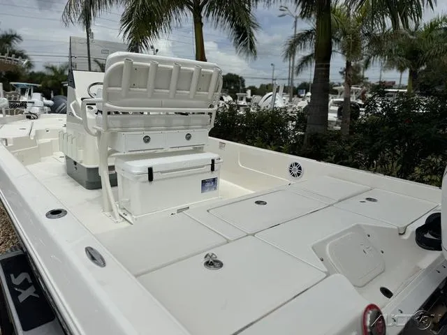 Slide: The Image of 2025 Skeeter SX230 boat deck with seating, storage, and palm trees in the background. - 23