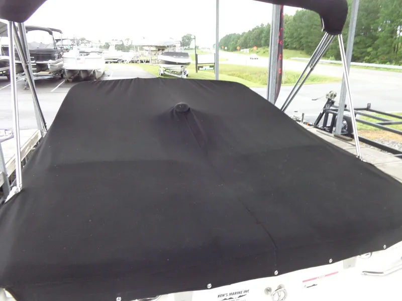 Slide: The Image of 2009 Glastron GT 185 boat with black cover in a marina setting. - 35