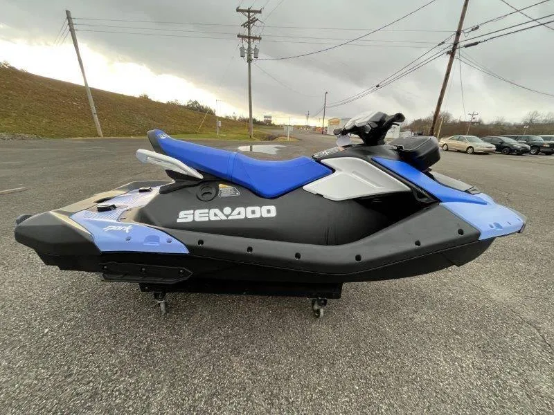 Slide: The Image of 2024 Sea-Doo Spark jet ski, blue and black, parked on asphalt. - 11