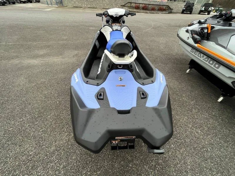 Slide: The Image of 2024 Sea-Doo Spark jet ski, blue and black, parked on asphalt. - 25
