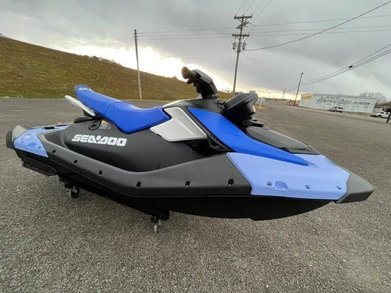 Slide: The Image of 2024 Sea-Doo Spark jet ski, blue and black, parked on asphalt under cloudy sky. - 26