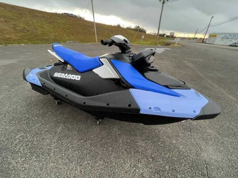 Slide: The Image of 2024 Sea-Doo Spark jet ski, blue and black, parked on asphalt. - 5