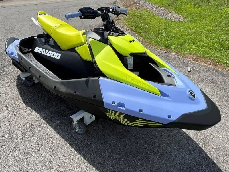 Slide: The Image of 2024 Sea-Doo Spark Trixx jet ski, vibrant yellow and blue design, parked on pavement. - 28