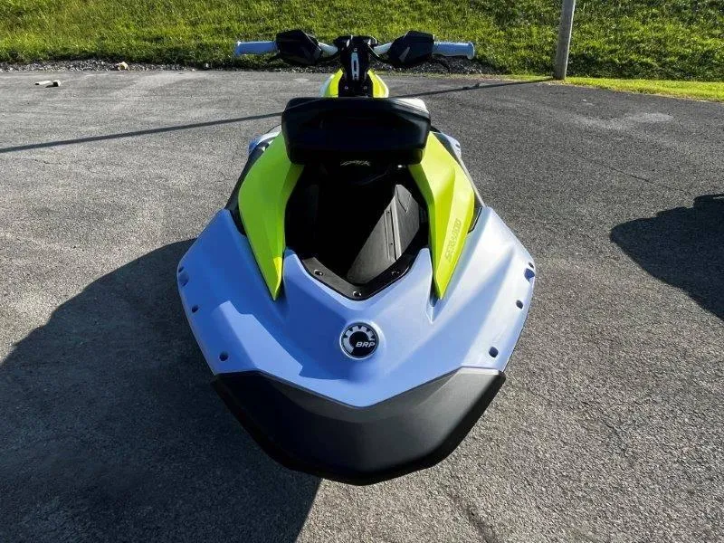 Slide: The Image of 2024 Sea-Doo Spark Trixx jet ski, vibrant yellow and blue, parked on pavement. - 14