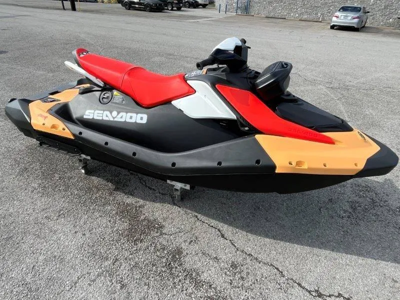 Slide: The Image of 2024 Sea-Doo Spark jet ski with red seat, black and orange body, parked on pavement. - 18